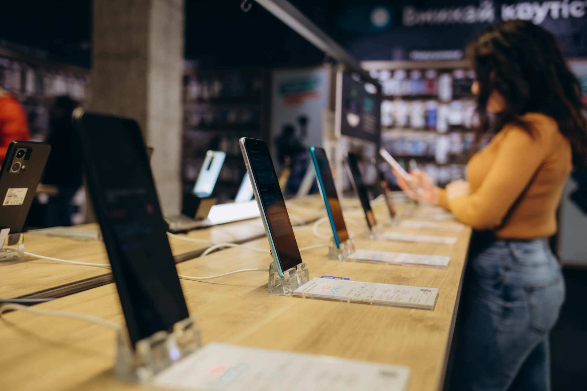 A customer browsing smartphones on a shop display table