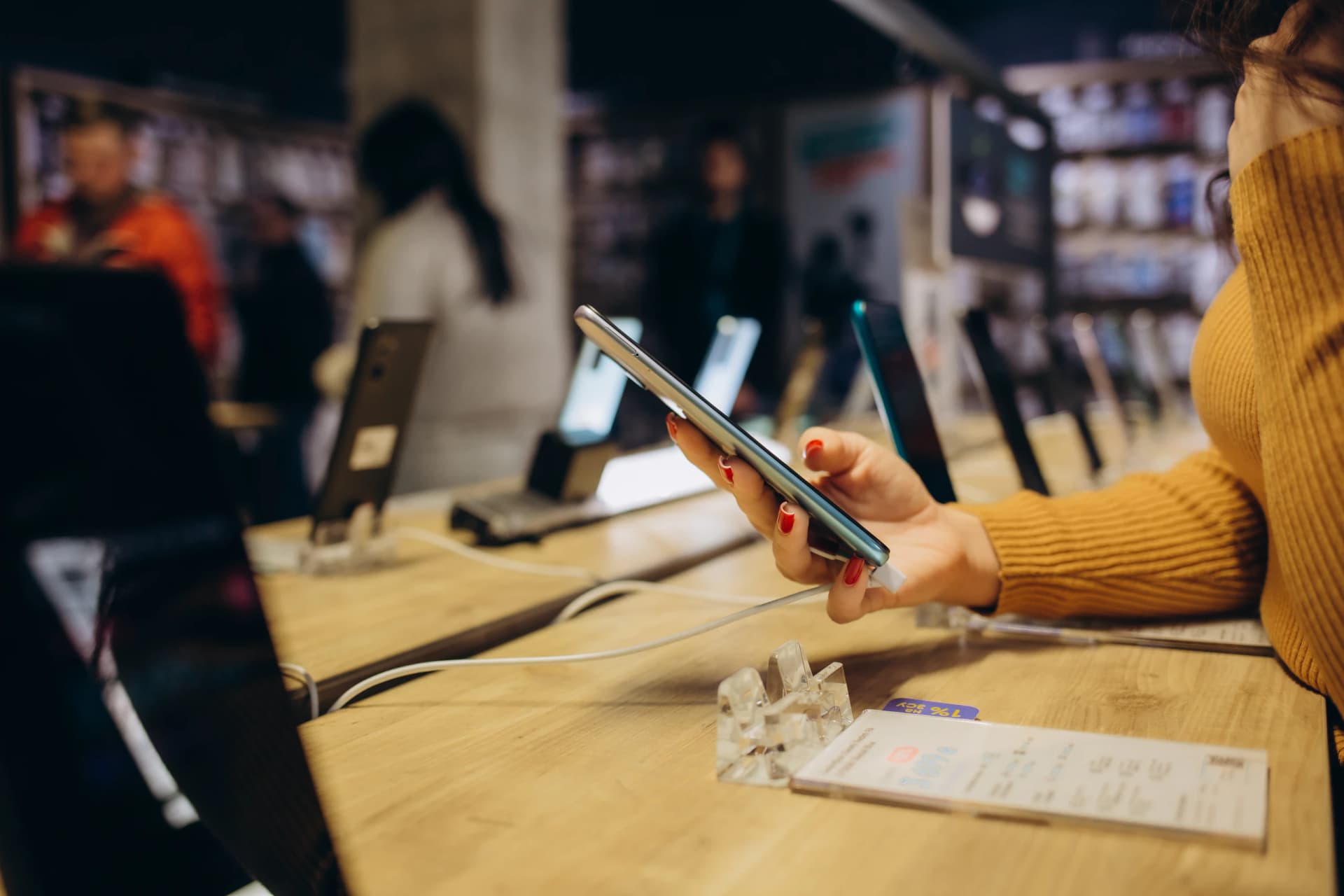 A customer trying out a smartphone at a shop display